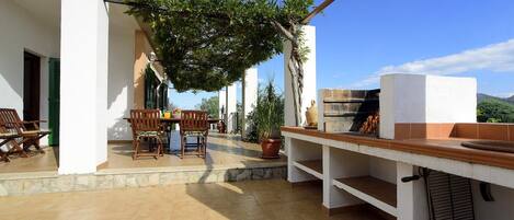 An outdoor patio with a table and chairs, a pizza oven, and potted plants.