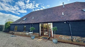 Un grand bâtiment en bois sombre, doté d’un toit en pente, d’une porte d’entrée en verre et d’une allée gravillonnée.