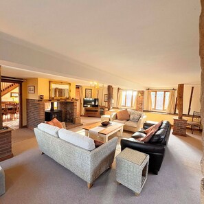 A spacious living room with a fireplace, a television, and comfortable seating including a sofa and a couch.