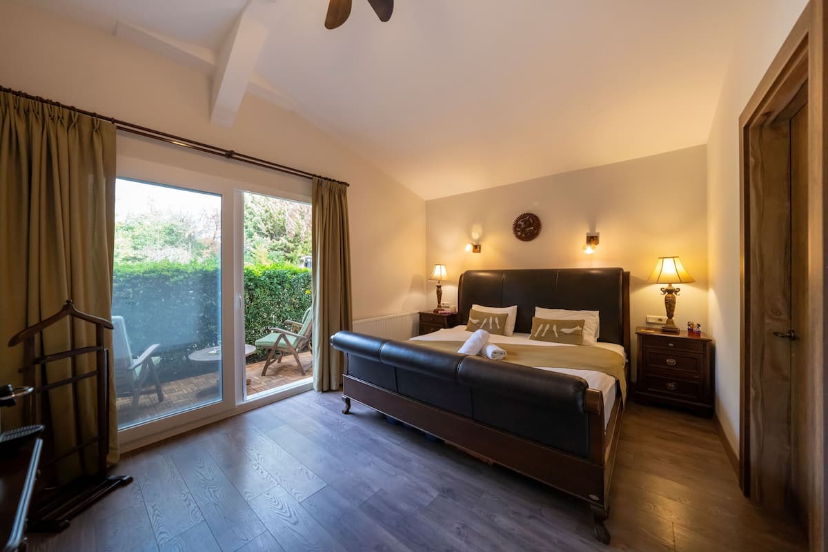 Un dormitorio con una cama grande, un ventanal corredero a un patio y dos lámparas de noche.