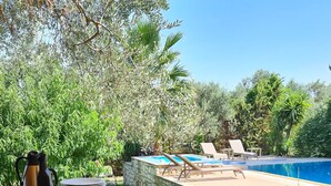 Una mesa de buffet con diversos alimentos, una piscina y un jardín al fondo.