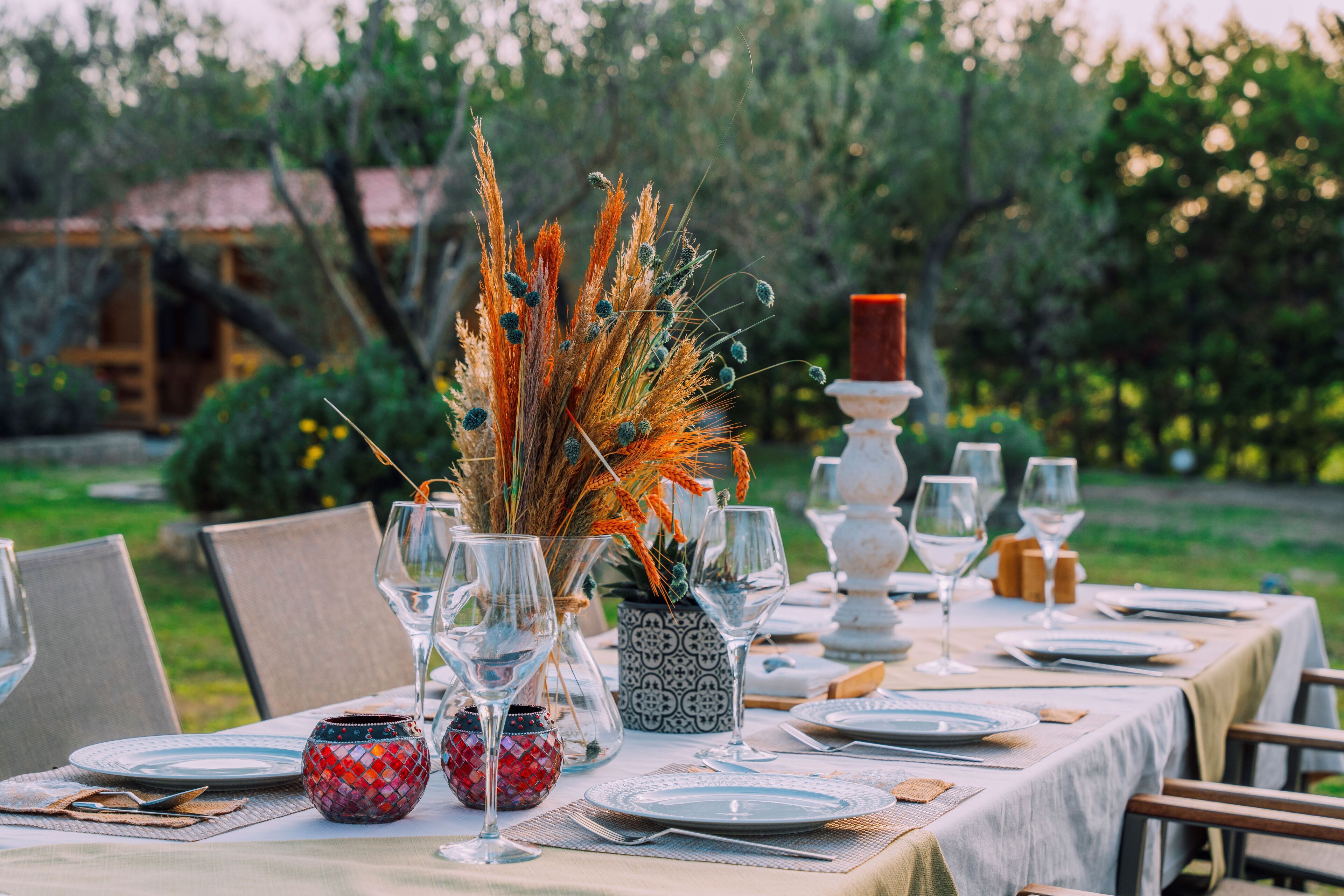 Una mesa preparada para una comida con copas, platos y un centro de mesa decorativo.
