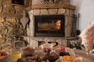 Una chimenea de piedra con una pantalla de televisión moderna, rodeada de diversos bocadillos y un vaso de bebida.