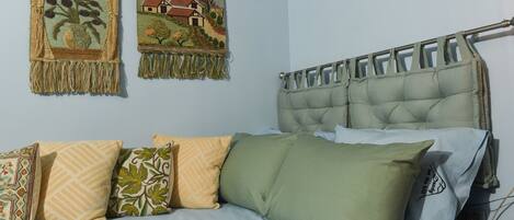 A bedroom with a bed, pillows, and two wall hangings.