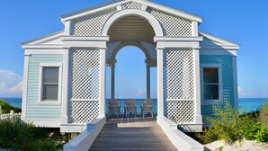 A small, light blue building with a wooden deck and a white lattice structure. - Directly Across From Beach With Gulf Views in Seaside, FL + 2 Adult Bikes! (Santa Rosa Beach)