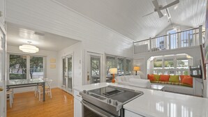 A spacious kitchen with a central island, a dining area with a table and chairs, and a seating area with a sofa and cushions. - Directly Across From Beach With Gulf Views in Seaside, FL + 2 Adult Bikes! (Santa Rosa Beach)