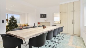 A modern dining area with a wooden table, black chairs, a Christmas tree, and a kitchen in the background. - Vacation home Staedenbergh in rural Staden! 10 pers (Staden)