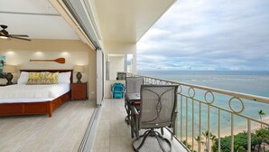 Un balcon avec un lit, une chaise et une vue sur l’océan.
