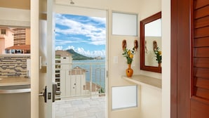 Un balcon donnant sur une plage et des immeubles, une porte en bois et un miroir accroché au mur.