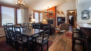A dining area with a wooden table and chairs, a fireplace, and a television in the background. - Zephyr Mountain Lodge, Condo | 3 bedroom Ski Slope Views (Premium rated Condo 2407) (Winter Park)
