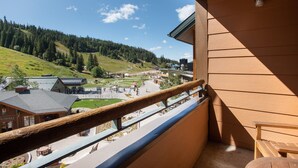 A balcony with a view of a mountainous landscape, a building with a sloped roof, and a wooden railing. - Zephyr Mountain Lodge, Condo | 3 bedroom Ski Slope Views (Premium rated Condo 2407) (Winter Park)