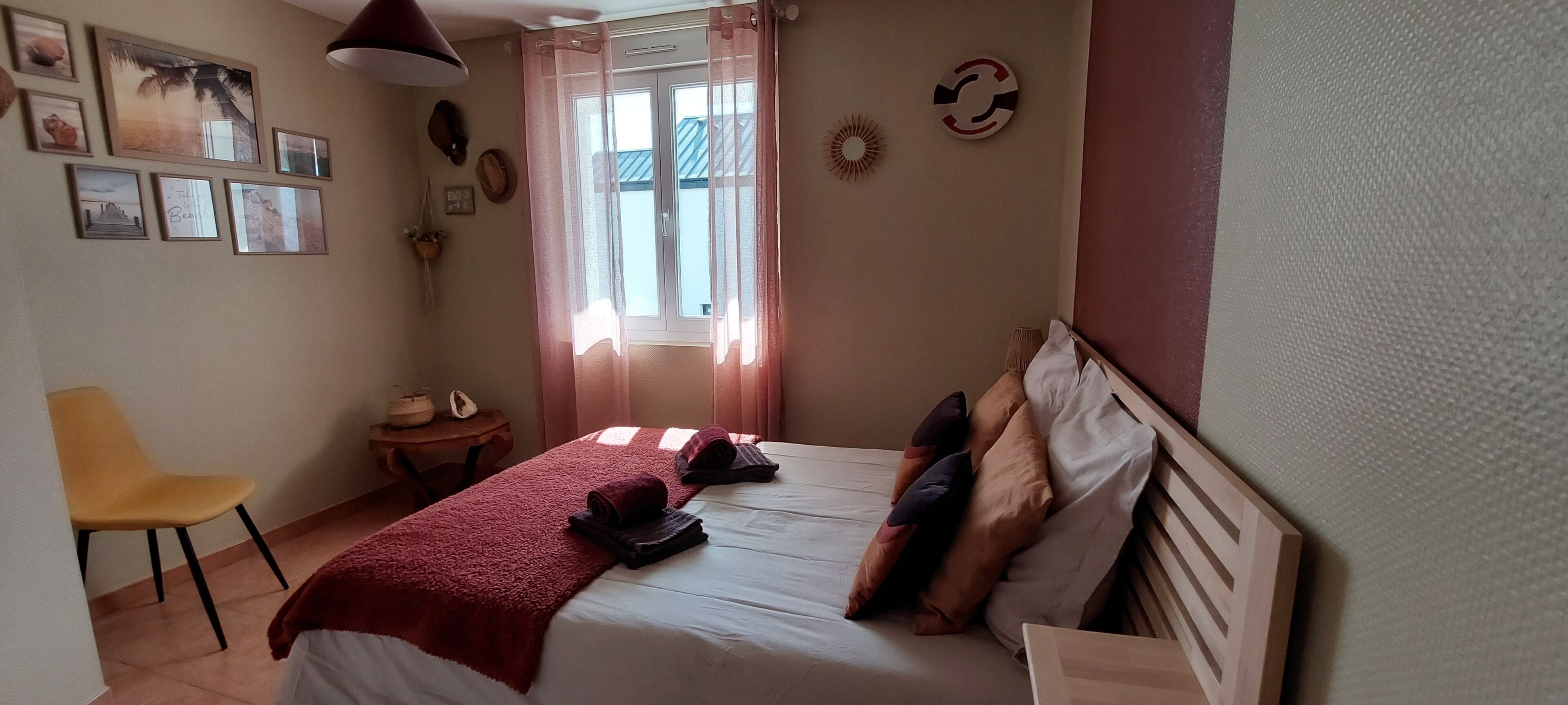 Une chambre à coucher comprenant un lit, une chaise, une petite table et divers éléments de décoration murale.