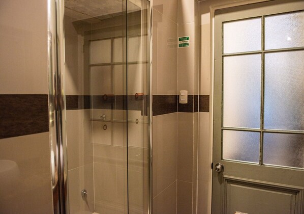 Un box de ducha con paredes de vidrio, una puerta y otra puerta con vidrio satinado.