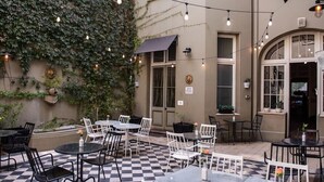 Un patio al aire libre con mesas y sillas, rodeado de un piso con estampado de cuadros.