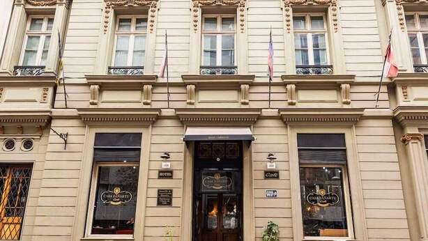 Un edificio histórico con una entrada central, ventanas amplias a ambos lados y un cartel que indica que es un hotel.