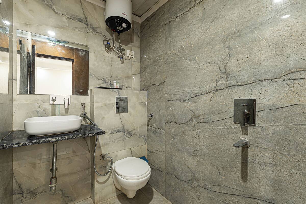 Un baño con lavamanos de mármol, inodoro, ducha y espejo.