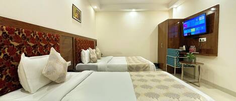 A hotel room with two beds, a TV, a desk, and a ceiling fan.