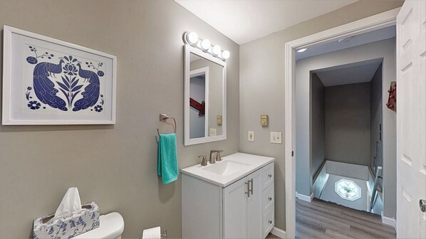 A bathroom with a white sink, a mirror with lights, and a framed floral artwork on the wall. - 5 Min Walk to Beach and Pier (Old Orchard Beach)