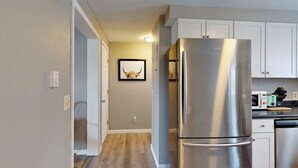 A modern kitchen with white cabinets, a stainless steel refrigerator, and a microwave on the countertop. - 5 Min Walk to Beach and Pier (Old Orchard Beach)