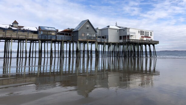 A waterfront property with a pier extending into the water, featuring multiple buildings and a restaurant. - 5 Min Walk to Beach and Pier (Old Orchard Beach)