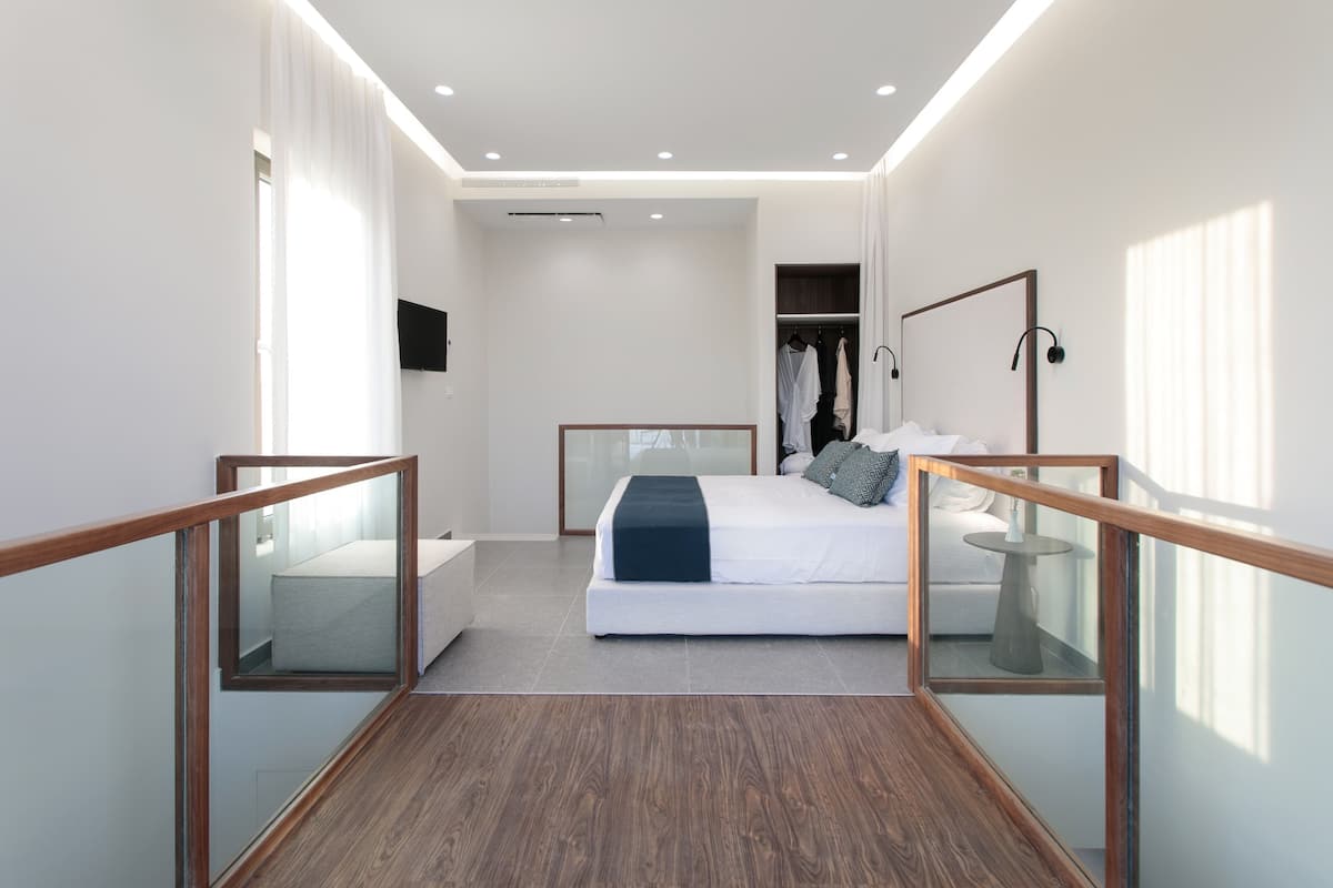 A modern bedroom with a large bed, a wardrobe, and a bedside table.