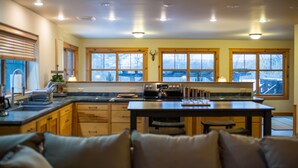 A kitchen with wooden cabinets, a central island, and large windows. - Beautiful 6-bed, 4.5-bath with private outdoor space.  5min walk to Main Street. (Lake Placid)