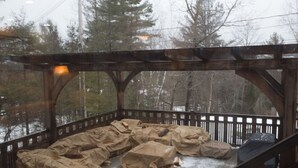 A covered outdoor seating area with stone benches and a wooden pergola. - Beautiful 6-bed, 4.5-bath with private outdoor space.  5min walk to Main Street. (Lake Placid)