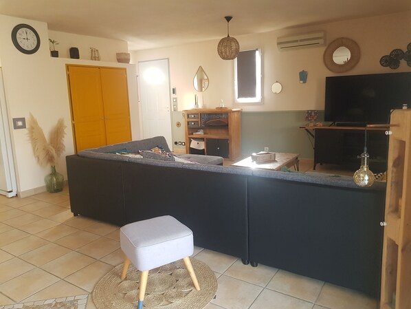 A modern living room with a grey sofa, a small grey ottoman, a wooden cabinet, a TV, and a decorative mirror. - House St Rémy de Provence with swimming pool 6 persons (Saint-Rémy-de-Provence)