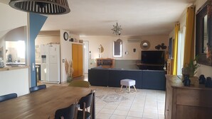 A modern kitchen with a dining area, a large TV, and a unique star-shaped light fixture.