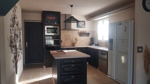 A modern kitchen with a central island, built-in ovens, a refrigerator, and a pendant light.