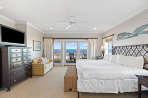 Een slaapkamer met een bed, een dressoir, een televisie en uitzicht op de oceaan.