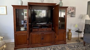 A living room with a wooden entertainment center, a television, and decorative items. - Beautifully Decorated Sm Dog Friendly Villa w/BBQ, BICYCLES & WiFi! (The Villages)