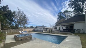 Ein Garten mit Swimmingpool, Whirlpool und überdachter Terrasse.