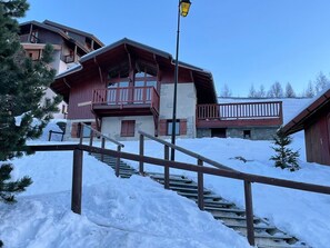 Een houten chalet met balkon, omringd door sneeuw.