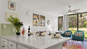 A modern kitchen with a central island, a dining area with a sofa and chairs, and a large window with a view of the outdoors.