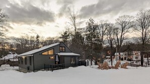 Una cabaña con techo nevado y un pequeño porche.