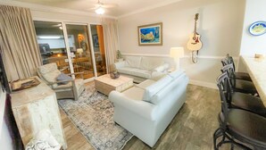 Een woonkamer met een bank, fauteuil, salontafel, en een gitaar aan de muur.