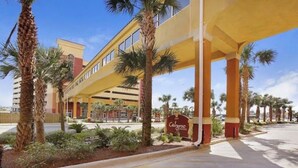 Een hotel met een overdekte doorgang, palmbomen en een bord waarop 'Calypso' staat.