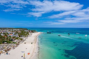 Praia particular, areia branca, espreguiçadeiras, guarda-sóis 