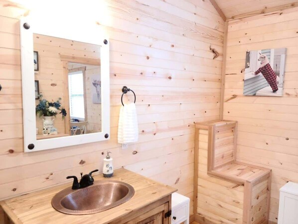 A wooden cabin interior with a wooden sink, a mirror, and a towel rack.