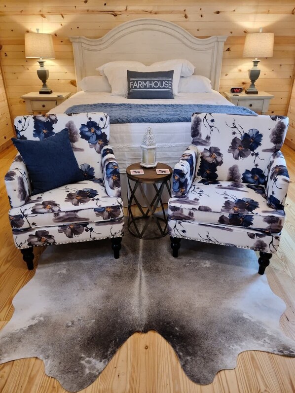 Quarto com uma cama, dois poltronas, uma mesinha e um tapete de couro de vaca.