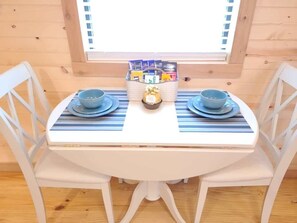 Ein Esstisch mit zwei blauen Tellern und Schüsseln, einer Snack-Korb und ein Fenster darüber.