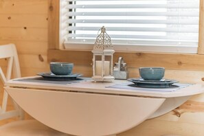 Una mesa con dos cuencos azules, una vela blanca y un farol decorativo en un ambiente de cabaña de madera.