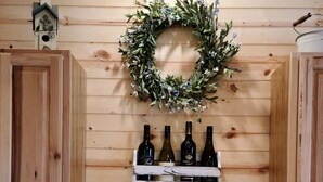 Una cocina con armarios de madera, un lavamanos blanco y una vinoteca con botellas y copas.