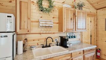 A kitchen with wooden cabinets, a granite countertop, a coffee machine, and a fire extinguisher.