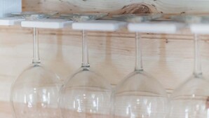 A row of empty wine glasses on a wooden shelf. - Romantic Cabin Right on Main St! (Fredericksburg)