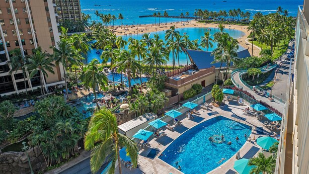 Un complexe hôtelier doté de plusieurs piscines, de palmiers et offrant une vue sur la plage.