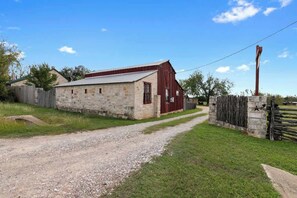 A stone building with a red barn, a gravel path, and a wooden fence.