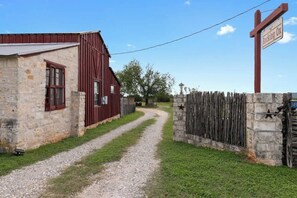 Ein Kiesweg führt zu einem roten Backsteinbauernhof und einem Steinhaus, mit einem Holzzaun und einem Schild mit der Aufschrift "Rocking Ox".