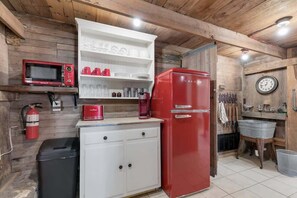 Eine kompakte Küche mit einem roten Kühlschrank, weißen Schränken, einer Mikrowelle und einer Kaffeemaschine.